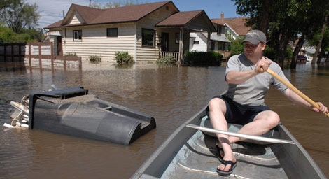 Mark Lints rows down Agricultural Street following a torrential downpour that caused flooding in Yorkton, Saskatchewan on Friday, July 2, 2010. Lints, his wife Edralyn, and their three-year-old son are three of many Yorkton residents whose homes were severely damaged by the flood. The city has declared a state of local emergency after a massive storm dumped 150 millimetres of rain in just 30 minutes. (THE CANADIAN PRESS/Mark Taylor.)